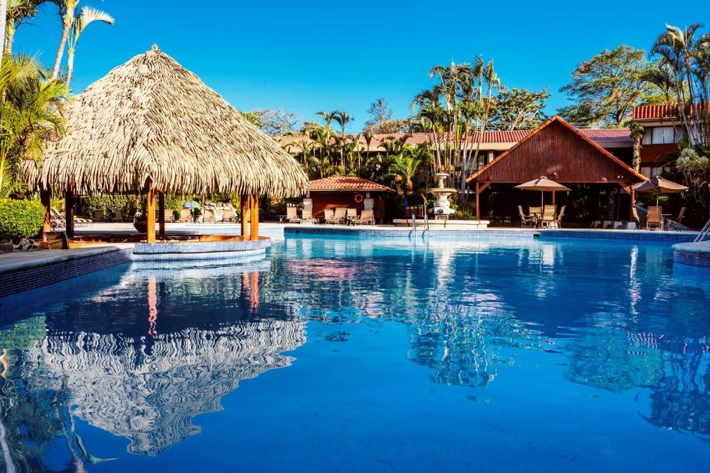 圣何塞Hilton Cariari DoubleTree San Jose - Costa Rica的茅草屋顶度假村的游泳池