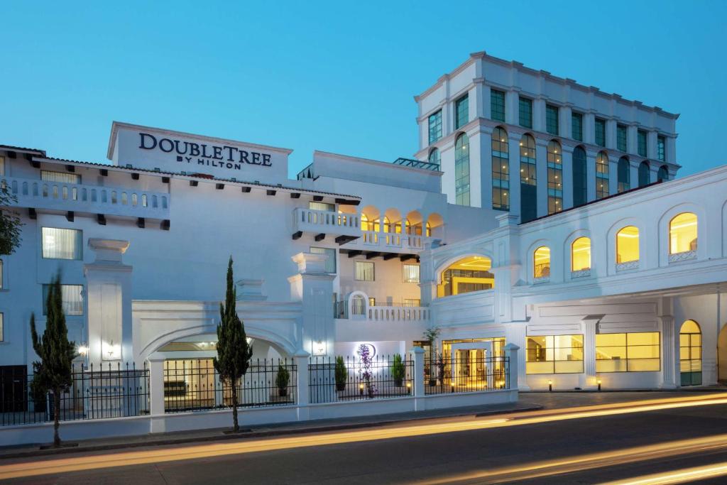 托卢卡Doubletree By Hilton Toluca的夜行的街道上一座白色的大建筑