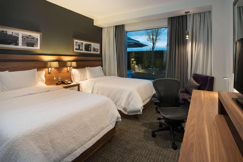 莱昂莱昂汉普顿酒店的酒店客房 - 带两张床、一张桌子和一把椅子