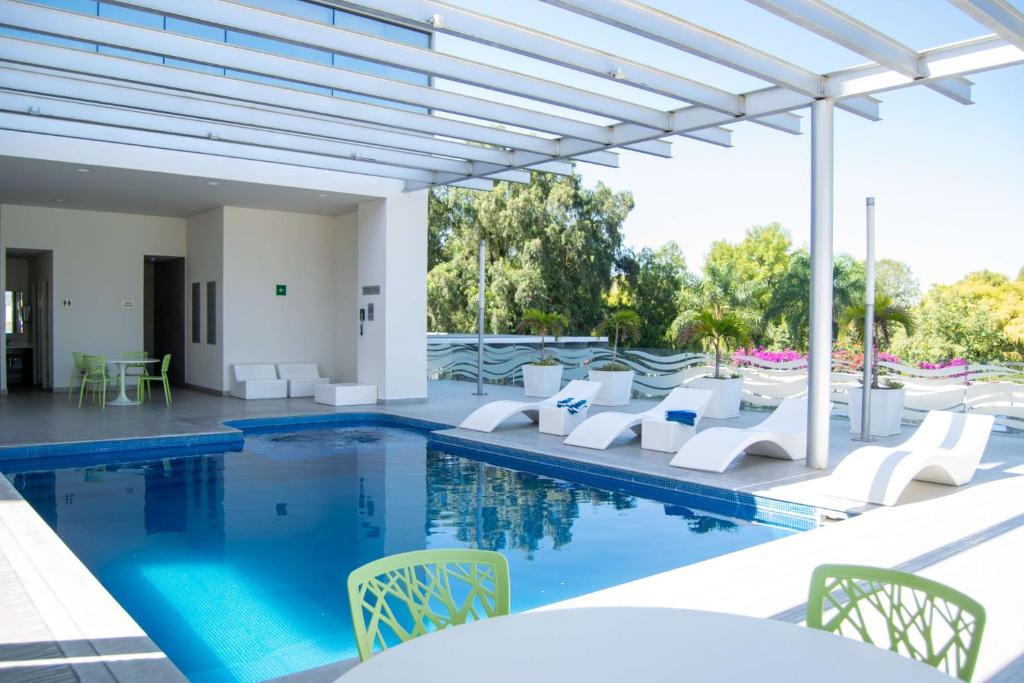 莱昂Hilton Garden Inn Leon Poliforum的一个带白色桌椅的游泳池和一个游泳池