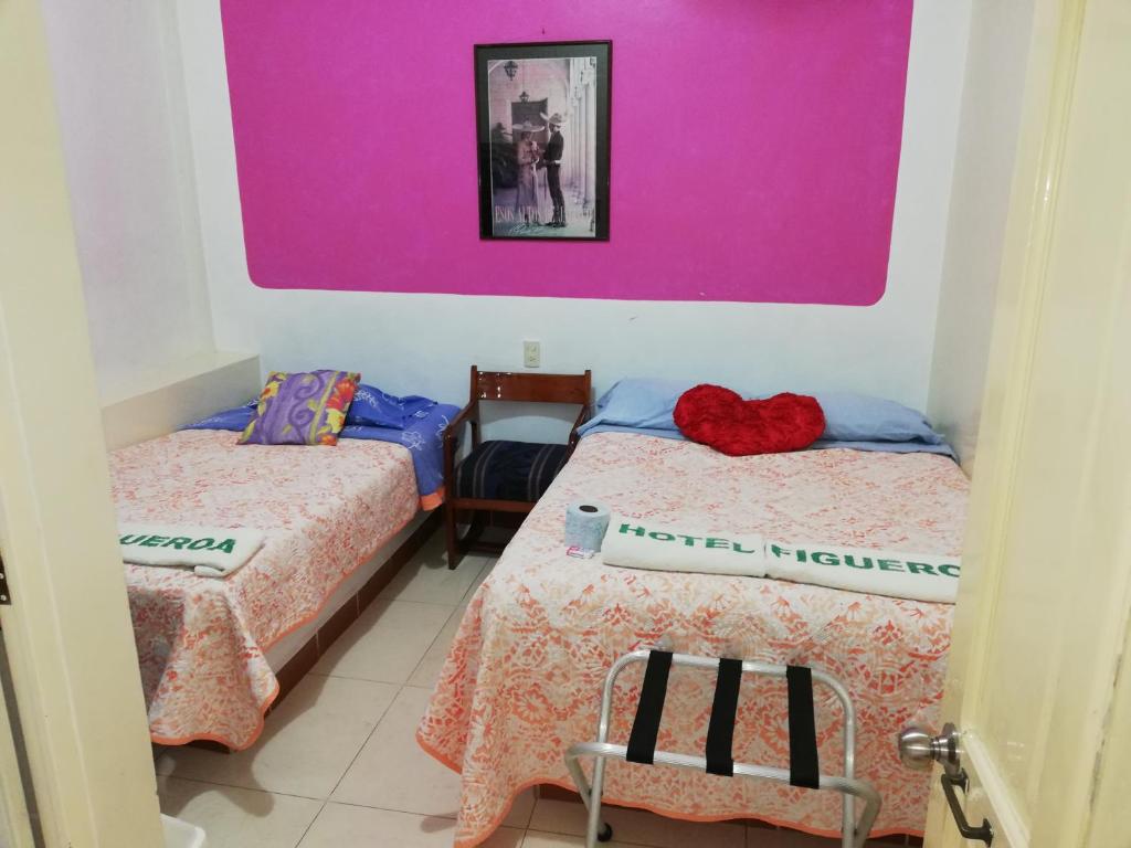 圣安德烈斯-图斯特拉菲格罗亚酒店 的一间设有两张床和粉红色墙壁的客房
