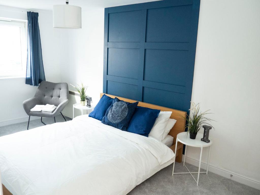 埃普瑟姆Stylish 2 bedroom apartment in the heart of Epsom town centre的一间卧室配有一张大床和蓝色床头板