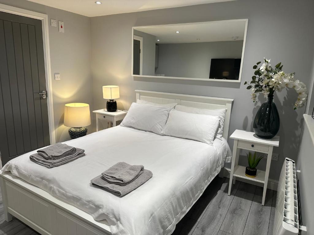 卢顿Modern Luxury Private Detached 1 Double Bedroom Studio Apartment - Super Fast Wifi的卧室配有白色床和毛巾