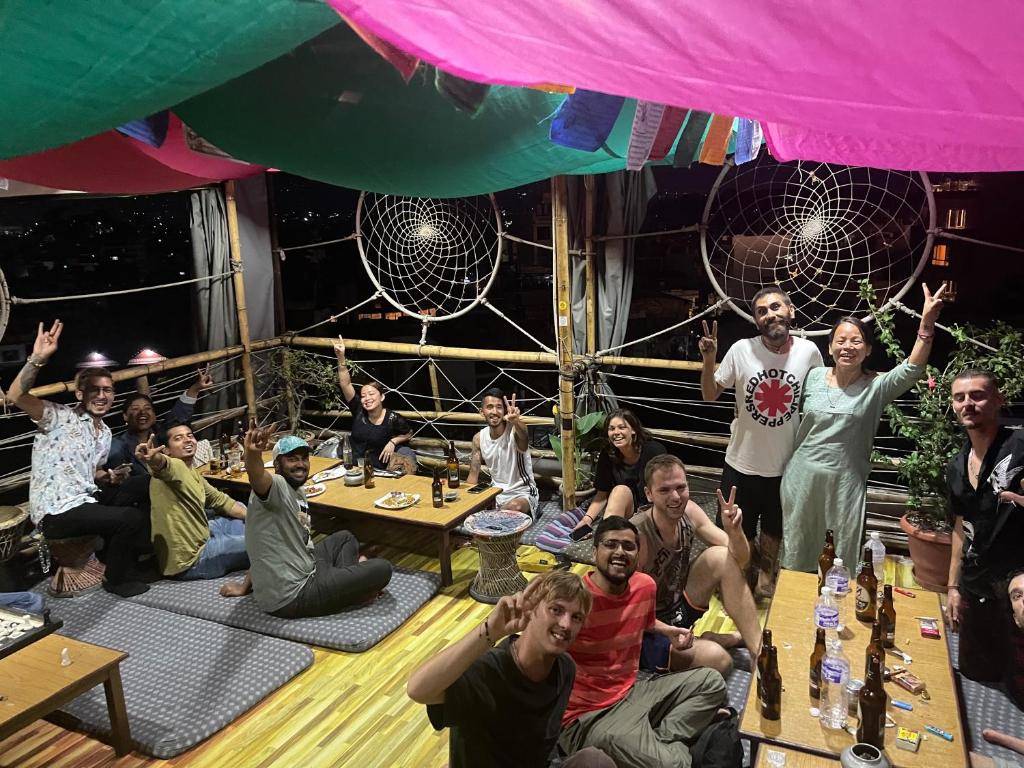 加德满都Planet Nomad Hostel的一群人坐在桌子旁,手放在空中