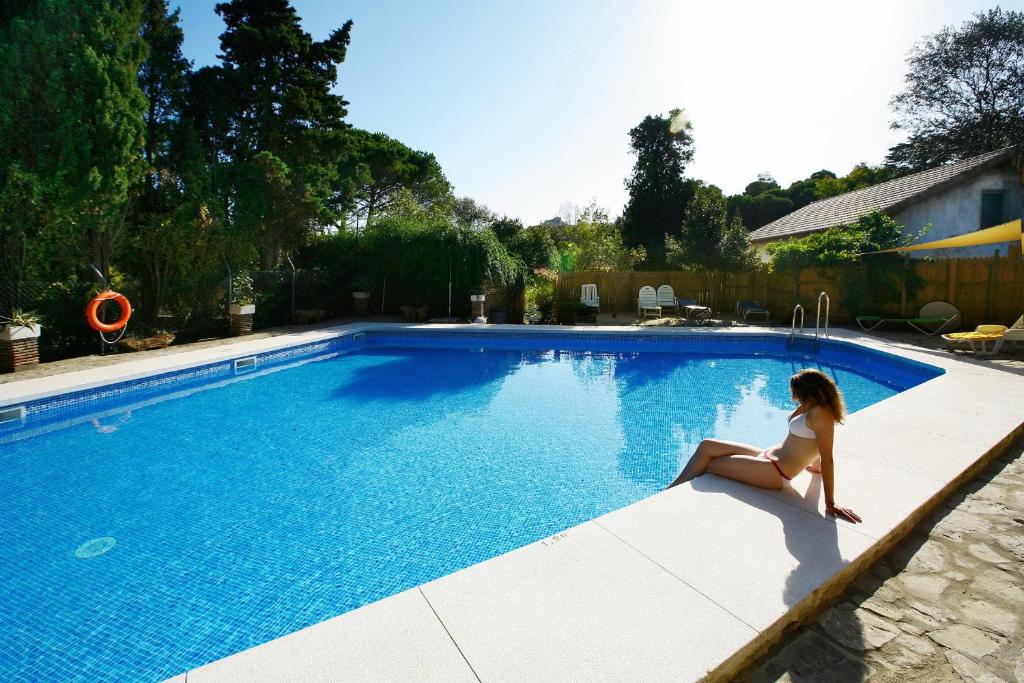 阿尔赫西拉斯康布里乡间赫塔格朗德酒店的坐在游泳池边缘的女人