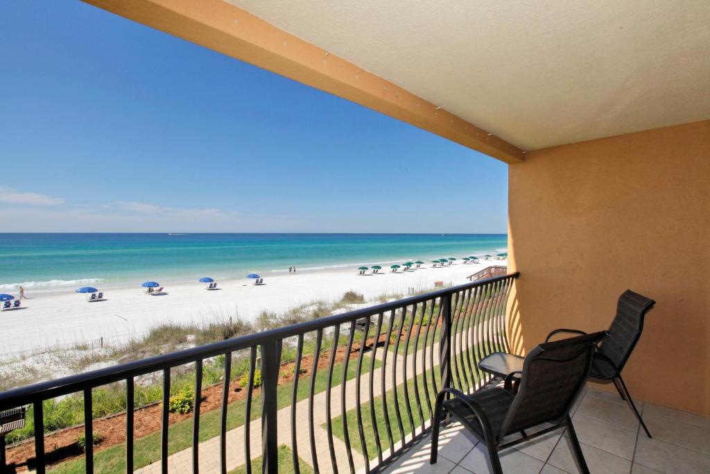 德斯坦狭长地带自助游珊瑚礁俱乐部度假酒店的阳台配有两把椅子,享有海滩美景