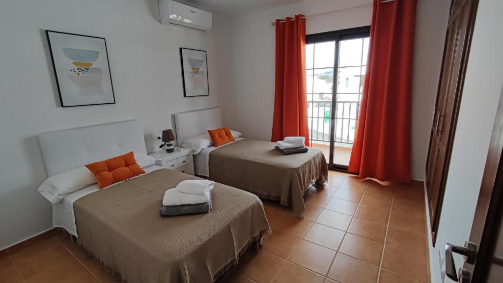 亚伊萨Villa Tingafa的客房设有两张床和一个带红色窗帘的窗户。
