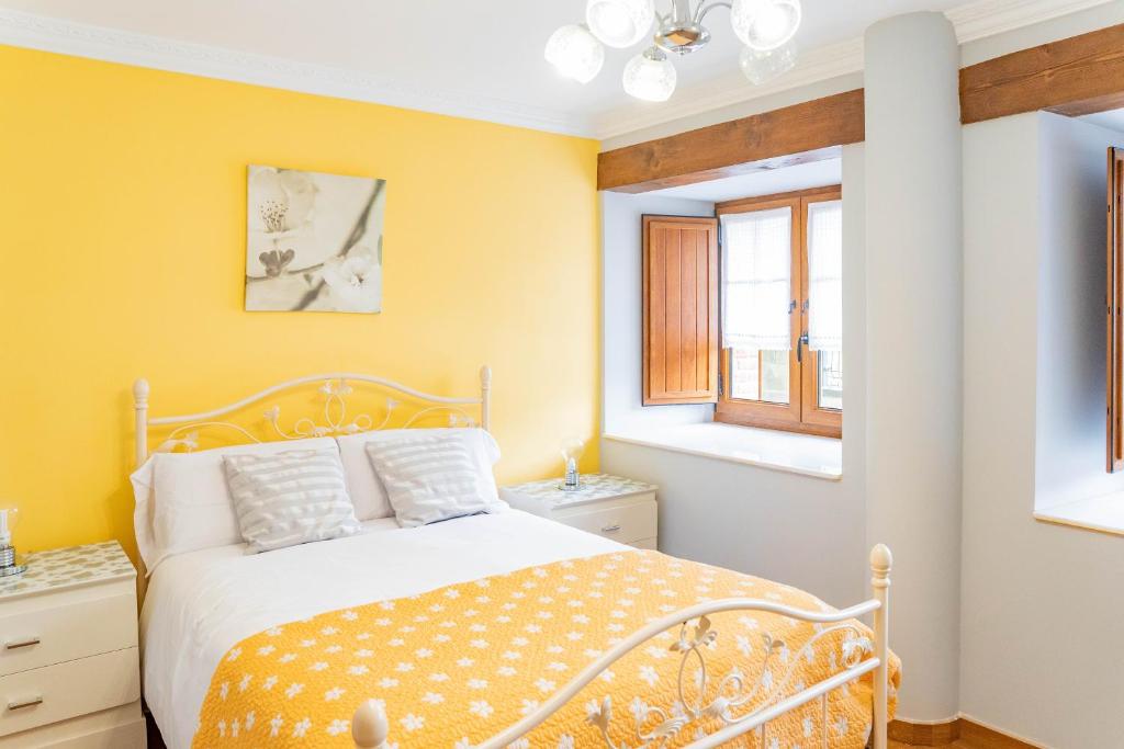 SobarzoLa Casita Verde de Cabárceno的黄色卧室设有床和2扇窗户