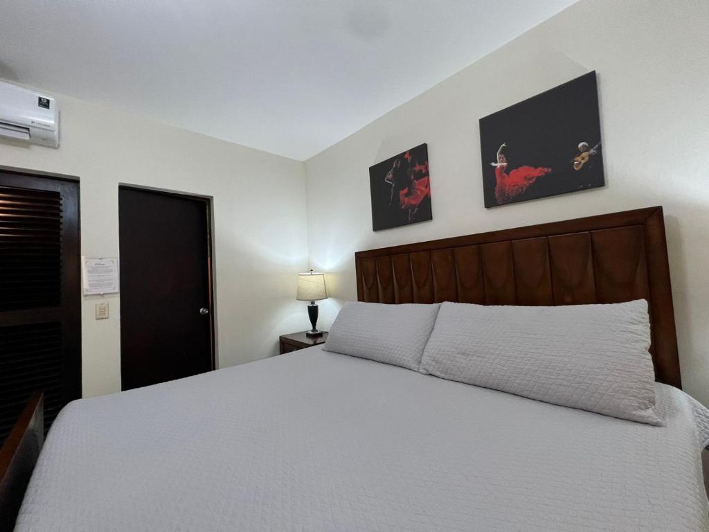圣萨尔瓦多Hotel Casa Pamplona的卧室配有白色的床和墙上的两张照片