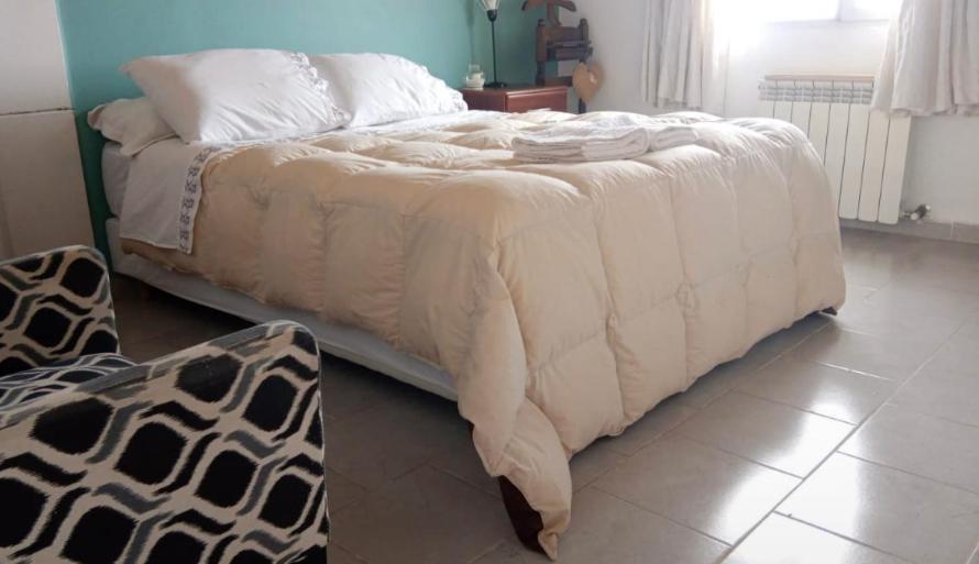 埃尔卡拉法特CALAFATE WIFI Depto 2 personas的卧室内的一张带白色棉被的大床