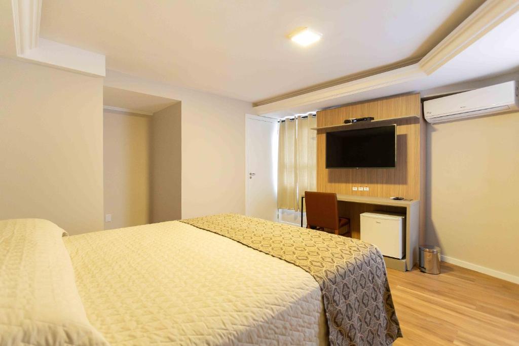 圣玛丽亚Hotel Dom Rafael Executivo的一间卧室配有一张床和一台平面电视