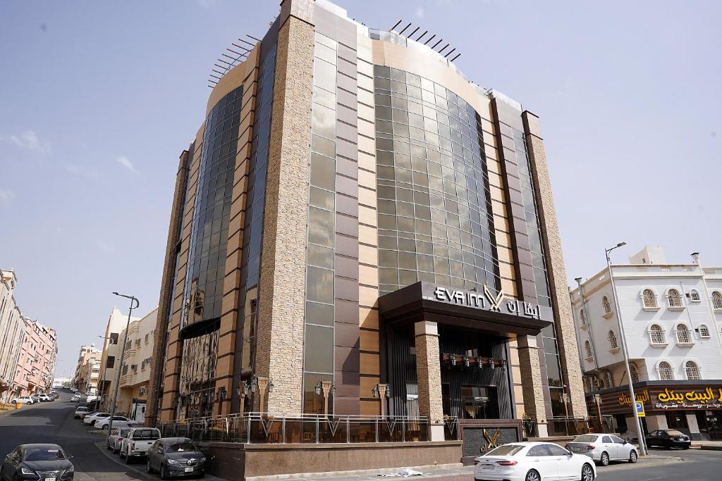 艾卜哈فندق إيفا إن的一条城市街道上的大型建筑,有车辆停放