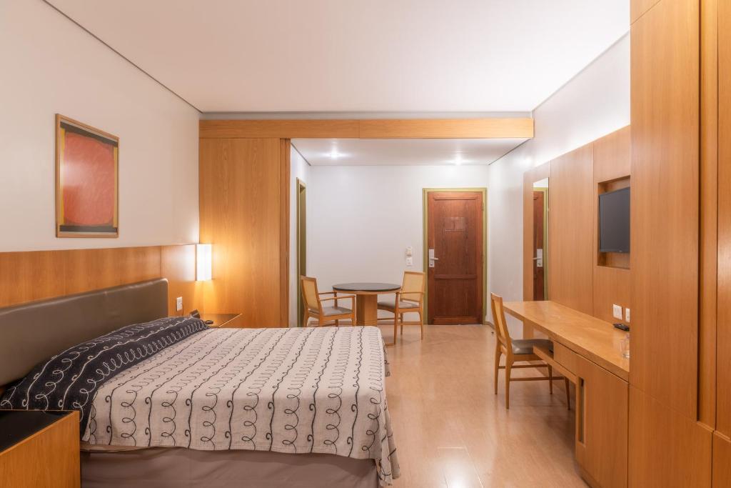 圣保罗DELPLAZA Excelsior São Paulo - By Monreale的卧室配有一张床和一张桌子及椅子
