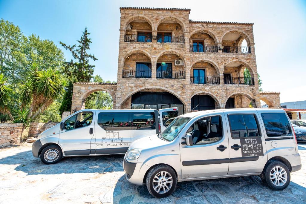 斯巴达Stone Palace Hotel Free Shuttle From and to Athen's Airport的两辆白色货车停在大楼前