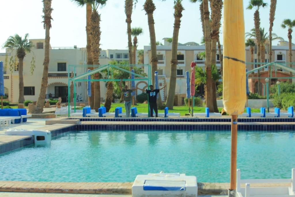 赫尔格达Mashrabiya Hotel的棕榈树泳池和背景人士