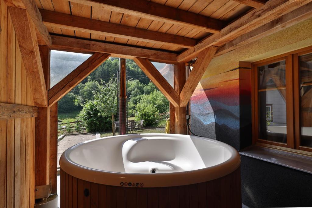 SoultzerenLe Chalet du Tanet spa sauna terrasse en Alsace的窗户客房内的大浴缸