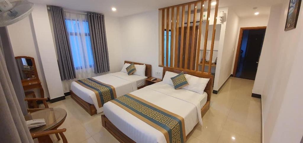 莲三Luxury hotel Phú Yên的酒店客房设有两张床和一张桌子。