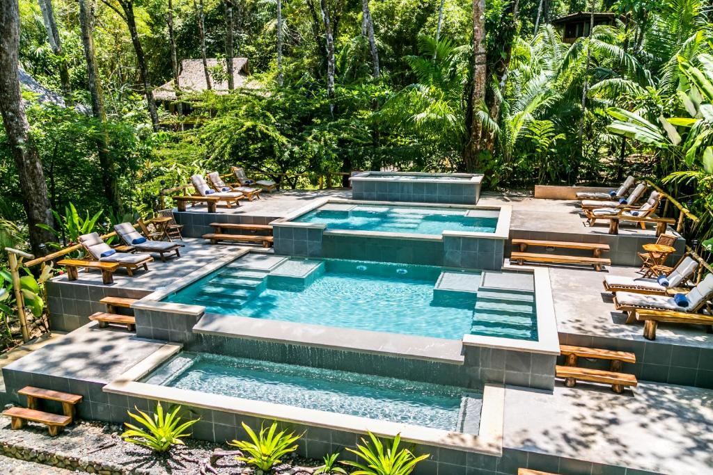 德雷克库帕阿波尔海滩雨林度假酒店的一个带躺椅的无边泳池和一个度假村