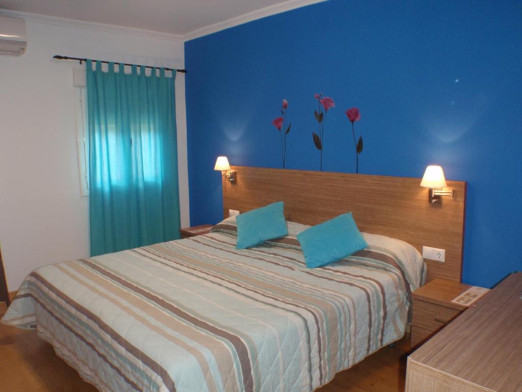 昆卡伊尔林拓阿罗家民特乡村酒店的一间卧室配有一张蓝色墙壁和墙上鲜花的床。