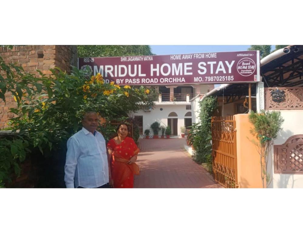 奥拉奇哈Mridul Homestay Orchha, Madhya Pradesh的站在房子前面的男人和女人