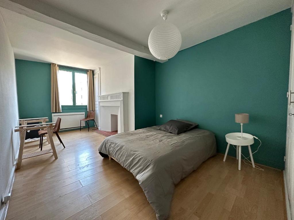 特鲁瓦Chambre dans maison originale en centre ville的一间卧室设有绿色的墙壁、一张床和一张桌子