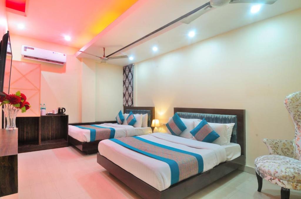 新德里Staybook Hotel Aira, Paharganj, New Delhi Railway Station的酒店客房,配有两张床和椅子