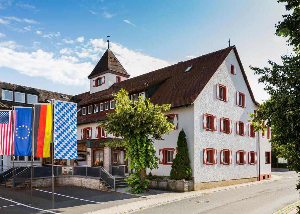 EdelsfeldWirtshaus & Hotel Goldener Greif的前面有旗帜的大型白色建筑