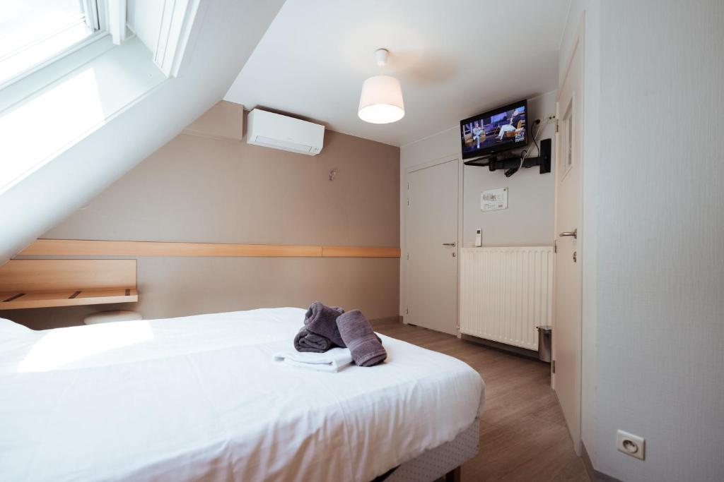 托尔豪特Hotel Brasserie De Beiaard的一间卧室设有两张床,墙上配有电视。