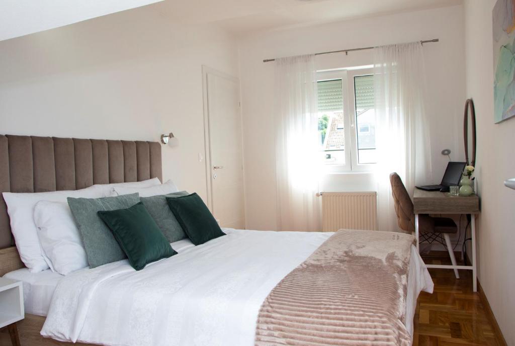 克鲁舍瓦茨Apartman MIA Centar的卧室配有带绿色枕头的大型白色床