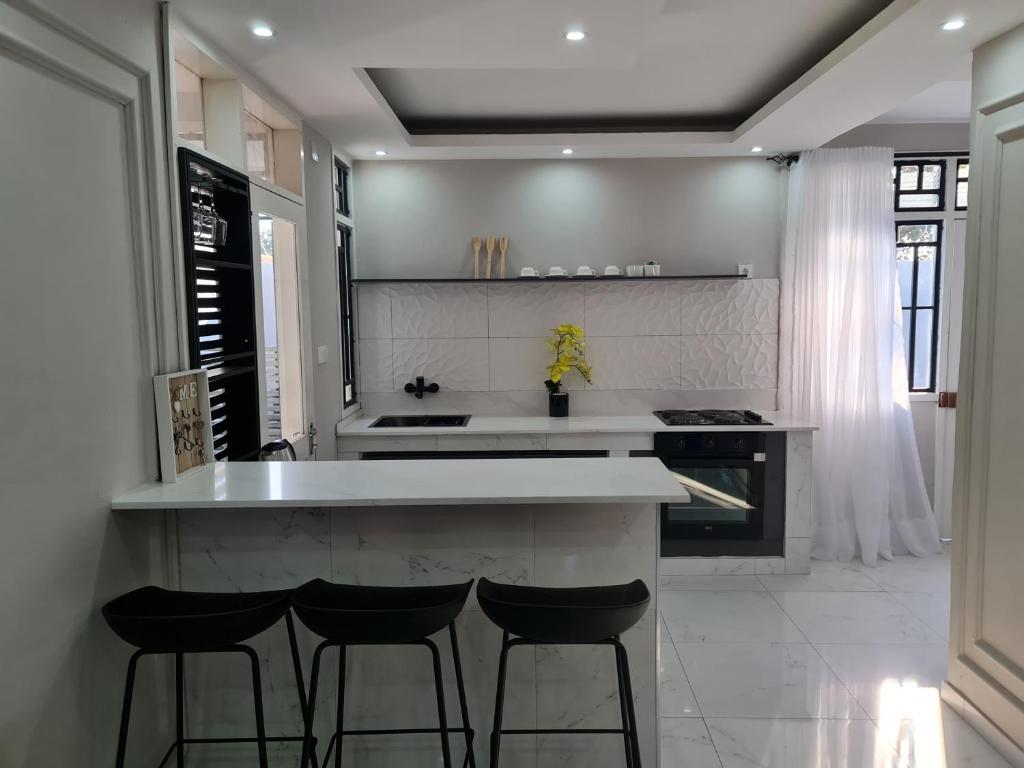 马普托Pousada Calma的厨房配有白色的柜台和凳子