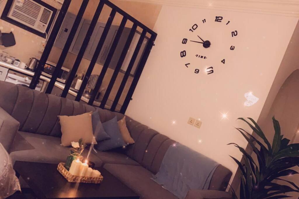 麦地那Taibah Apartment的客厅配有沙发和墙上的时钟