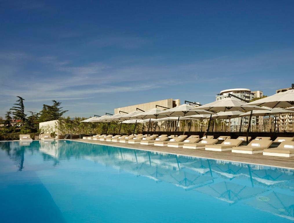 第比利斯第比利斯假日酒店 的一个带躺椅和遮阳伞的游泳池