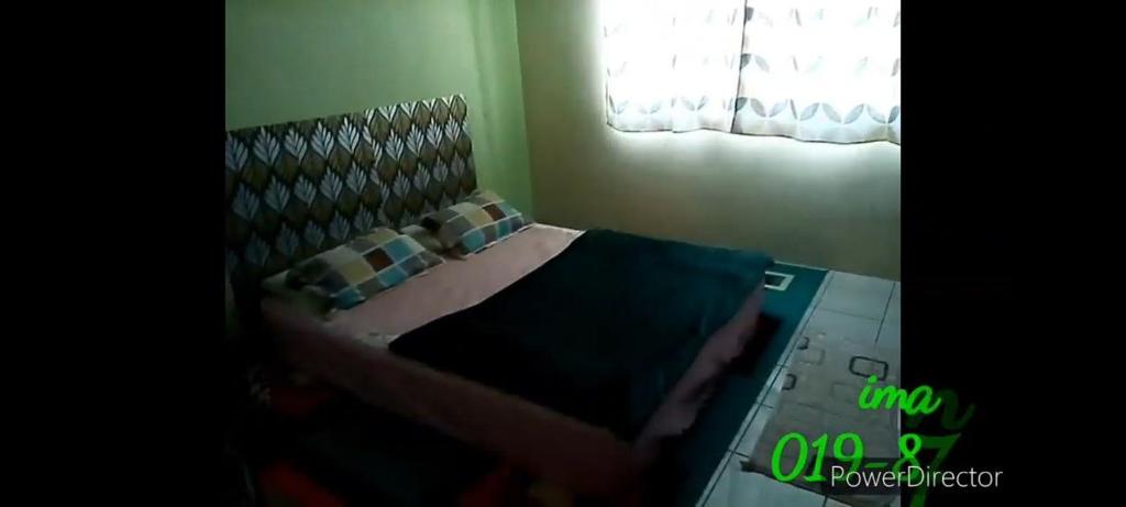 帕帕尔Iman Homestay的卧室配有带枕头的床铺和窗户。