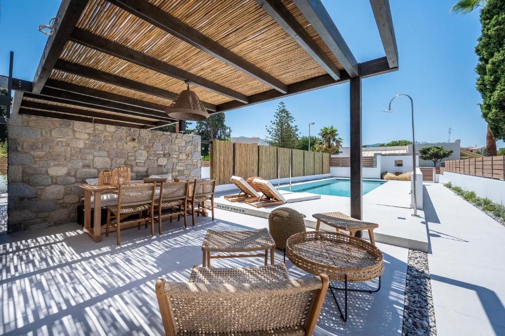 帕萨里迪RASTONI VILLAS BY AEGEAN HOUSES的一个带桌椅的庭院和一个游泳池