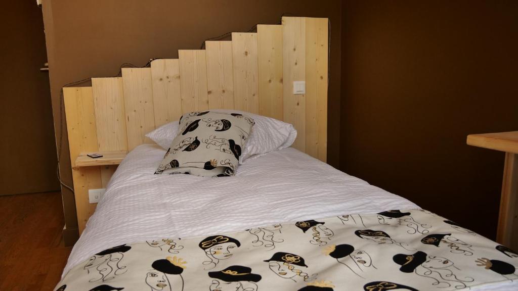 勒哈斯Relais des Monts du Lyonnais的一张带木制床头板和枕头的床