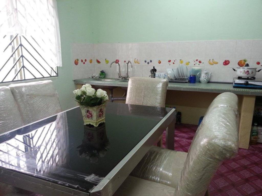 小笨珍Homestay Sri Perhentian Pontian的厨房配有一张桌子,上面放着花瓶