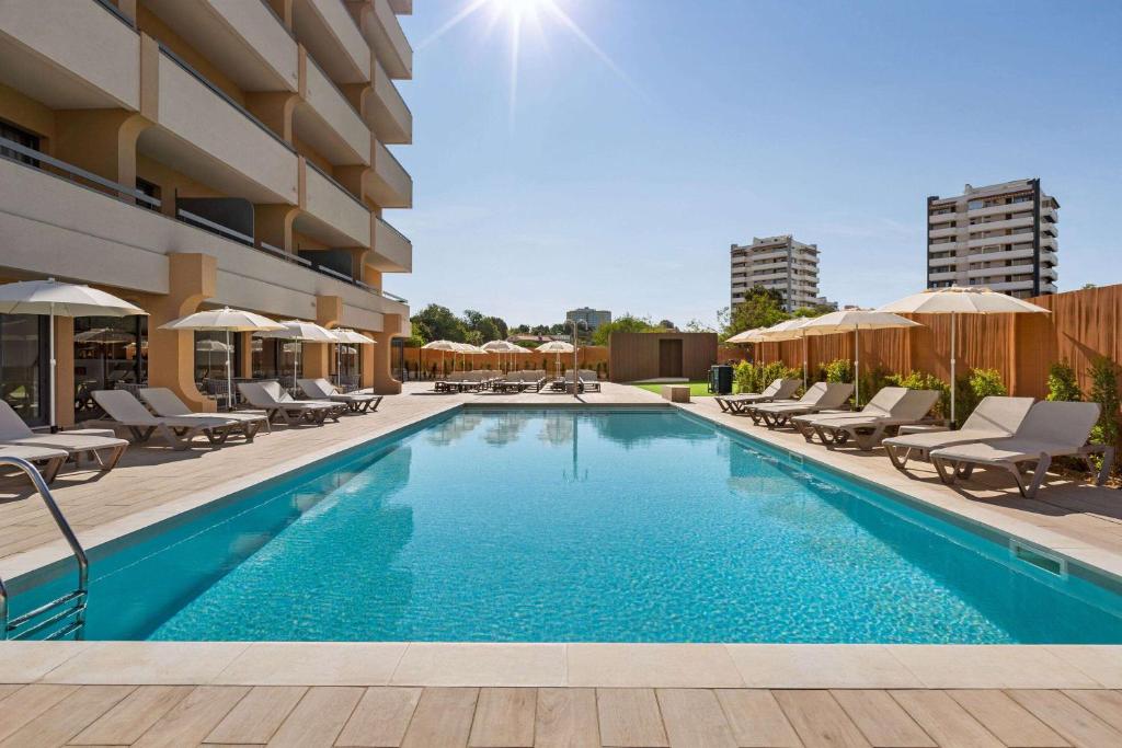 阿尔沃尔Wyndham Residences Alvor Beach的一个带椅子和遮阳伞的游泳池