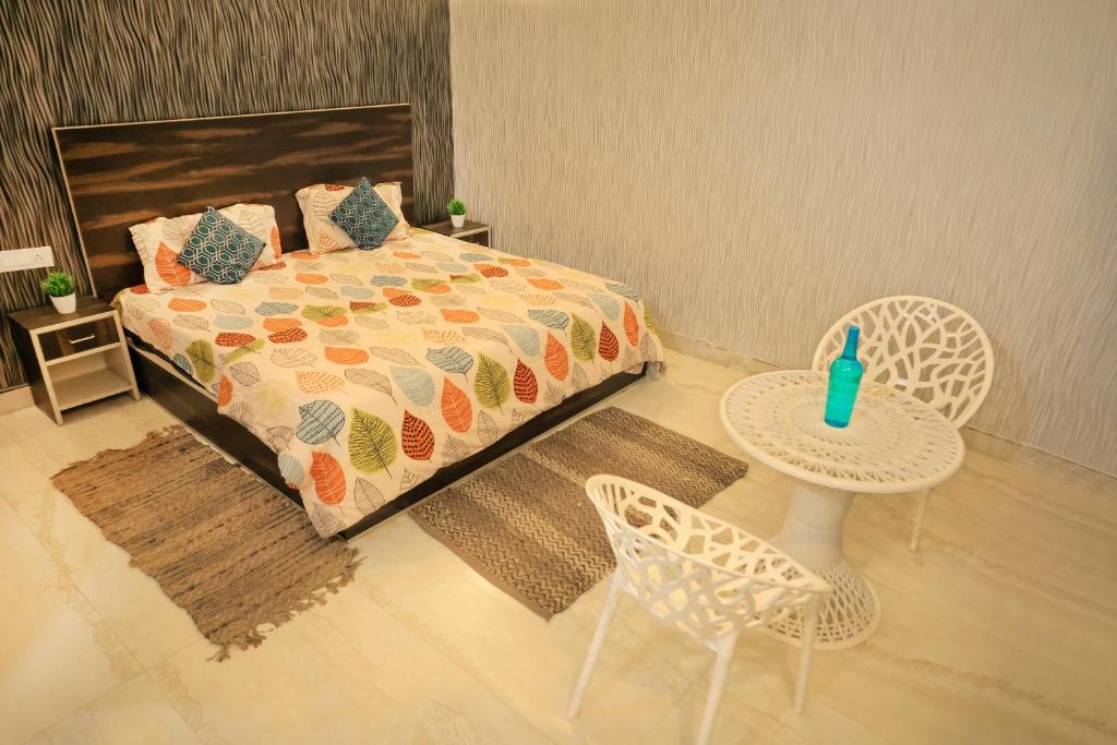 法里达巴德Aagman Stays By Kasa Lusso的卧室配有一张床和一张桌子及椅子