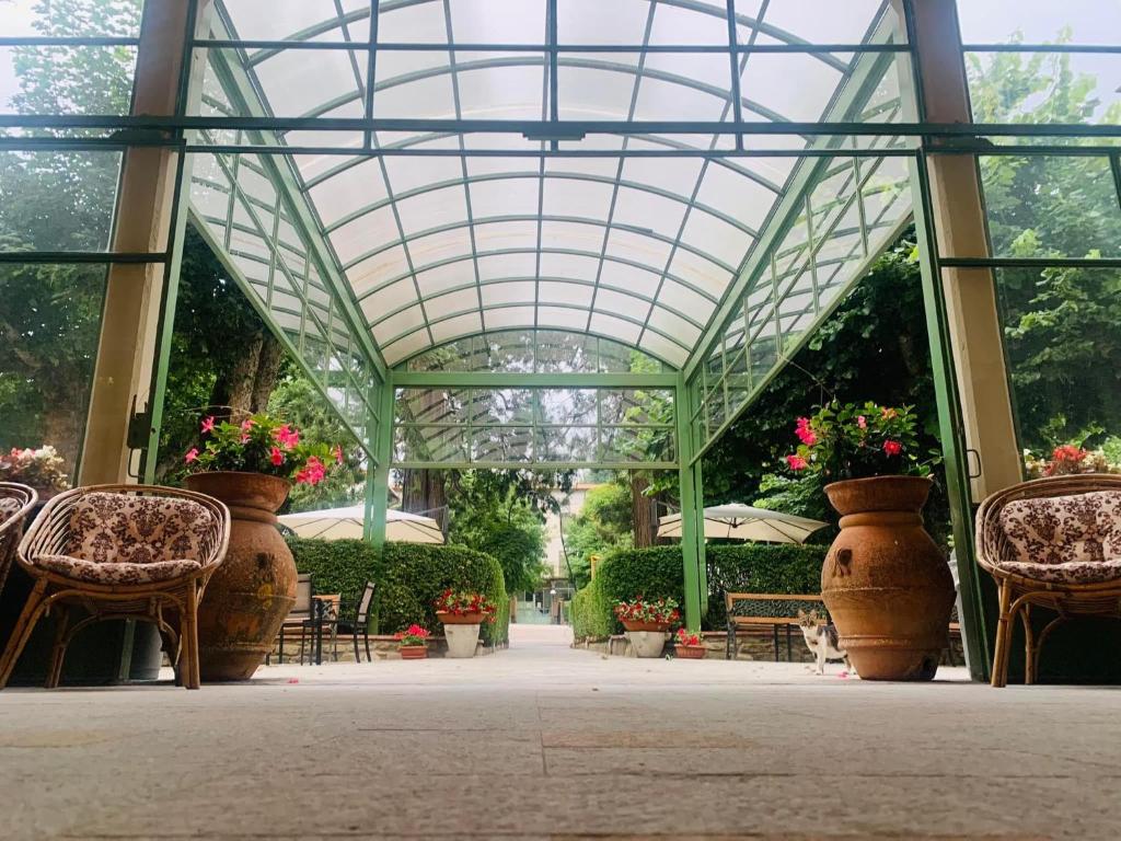 瓦隆布罗萨瓦隆布罗萨格兰德酒店的一个带大壶鲜花和椅子的温室
