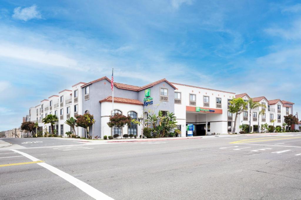 贺茂沙海滩赫莫萨比奇快捷假日及套房酒店的街道边的白色大建筑