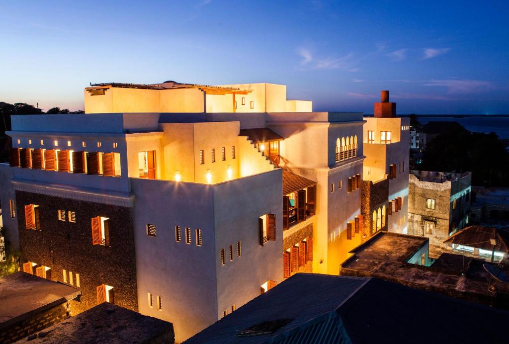 拉穆Swahili Dreams Apartments的一座白色的大建筑,灯火通明