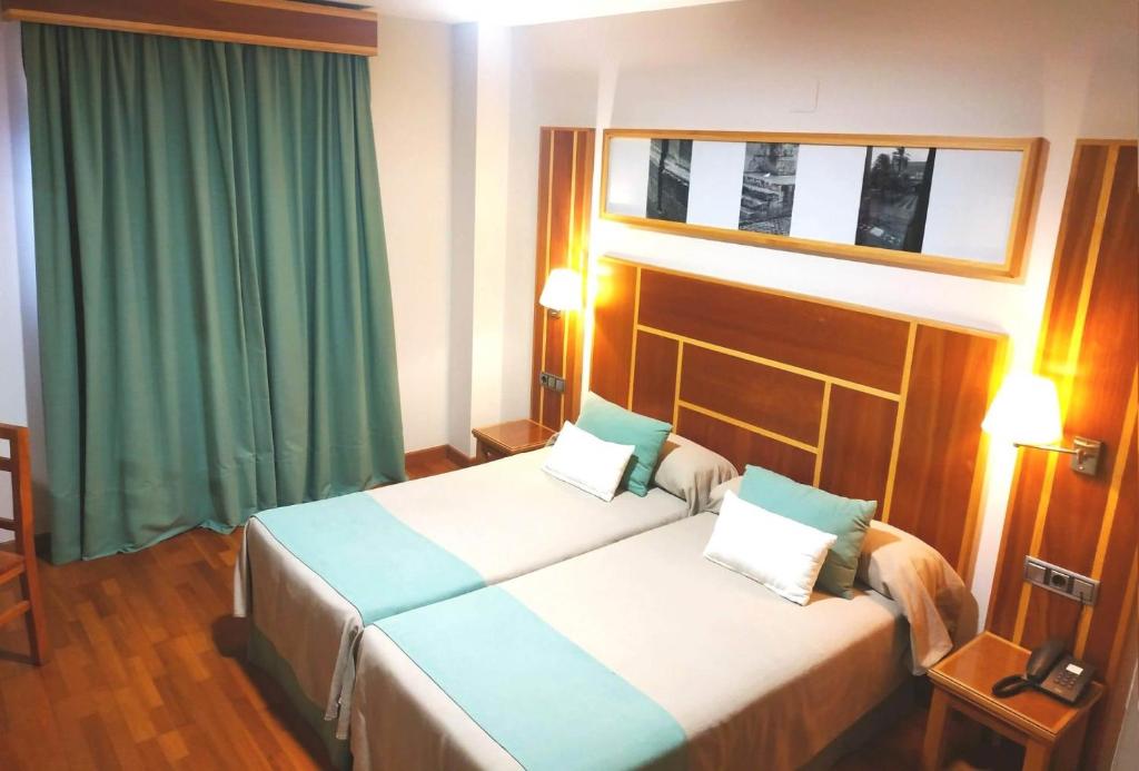 拉卡尔洛塔Hotel Carmen的酒店客房,设有两张床和绿色窗帘
