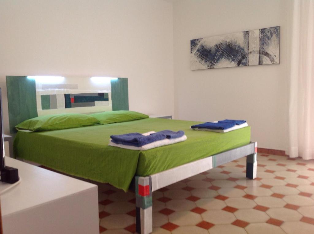 拉卡莱Casa Manni Torre Suda的一间卧室配有绿床和2条毛巾