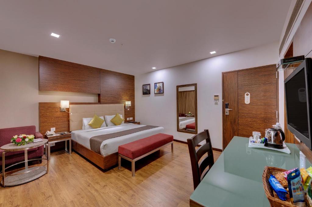 艾哈迈达巴德Hotel Suba Star Ahmedabad的酒店客房配有一张床铺和一张桌子。