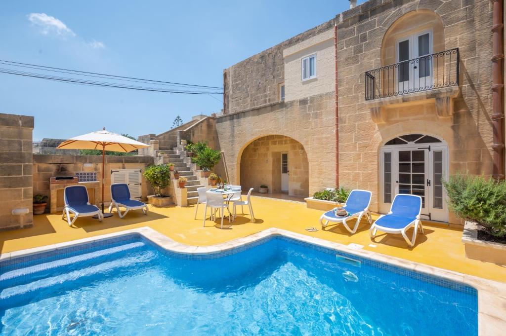 阿尔卜Dar ta' Betta Farmhouse with private pool的一座房子,设有游泳池、椅子和遮阳伞