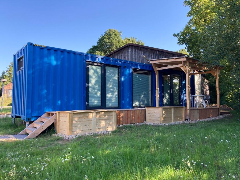 科堡Tiny House im Seecontainer mit Parkplatz, Glasfaser, Netflix, Veranda und gehobener Ausstattung的田野上装有蓝色集装箱的房屋