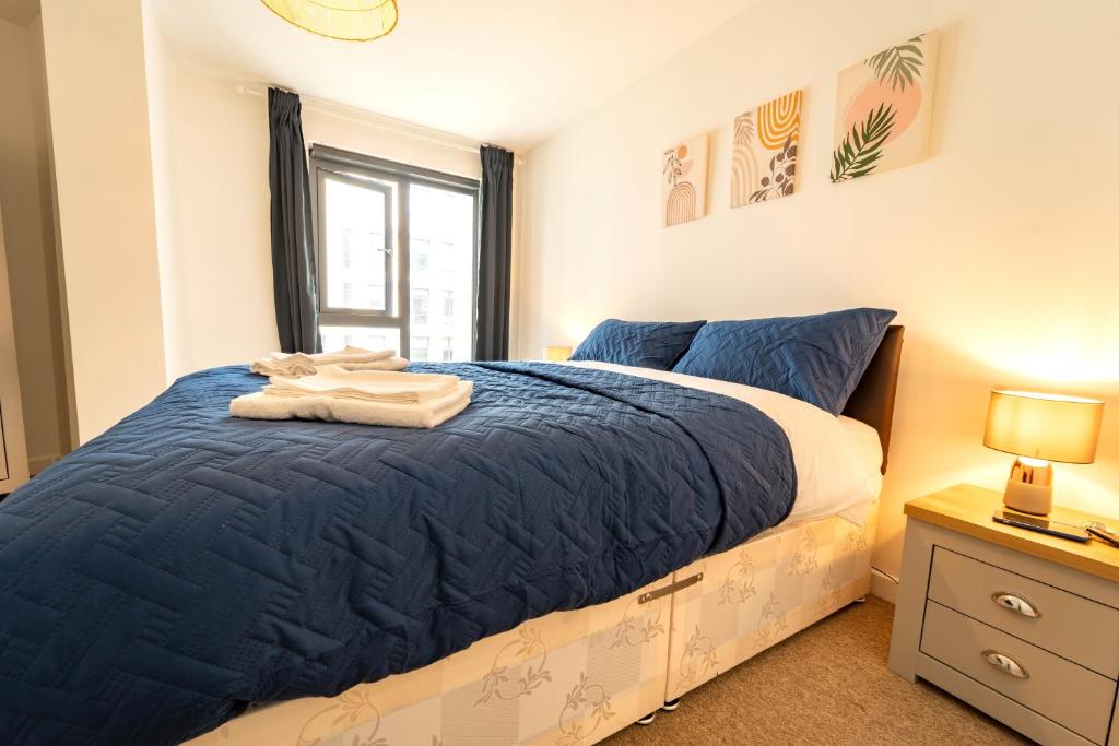 沃金Spacious Apartment in Woking Town Centre的一间卧室配有一张带蓝色床单的床和一扇窗户。