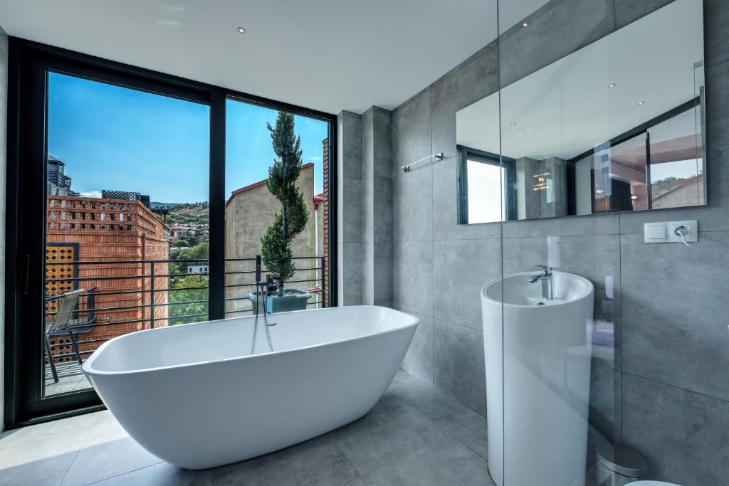第比利斯Mit Hotel Tbilisi的一间带白色浴缸和大窗户的浴室