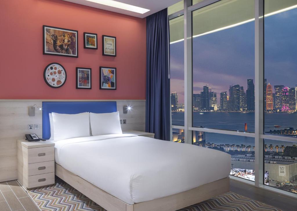 多哈Hampton By Hilton Doha Old Town的一间卧室设有一张大床和一个大窗户