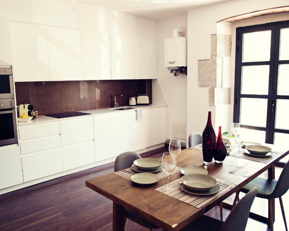 赫罗纳THE RIVERSIDE LODGE Cozy and spacious apartment的厨房配有木桌、盘子和酒杯
